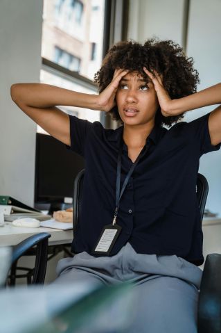 Young businesswoman looking stressed at her desk in a modern office.